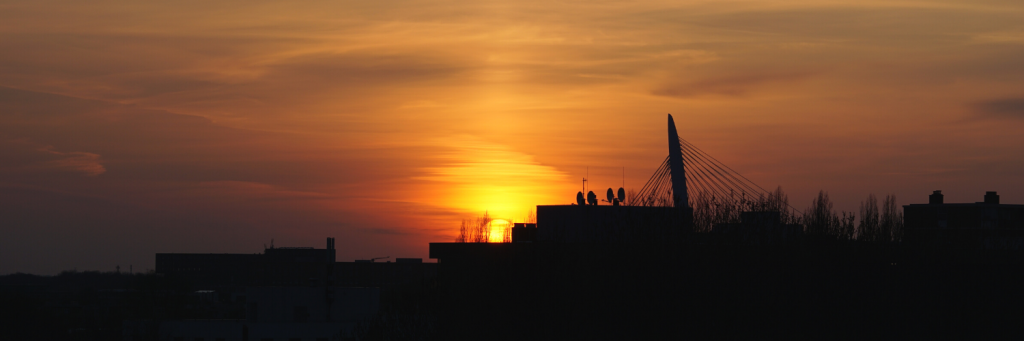 Foto van mijn uitzicht: skyline met Prins Clausbruf en daarachter de ondergaande zon.