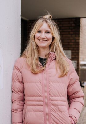 Foto van Josine van Boxmeer. Een vrouw met lange, blonde haren. Ze heeft een lichtroze winterjas aan.